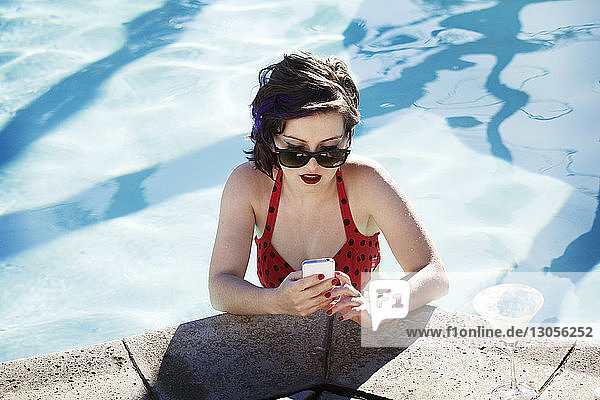 Junge Frau benutzt Smartphone im Schwimmbad