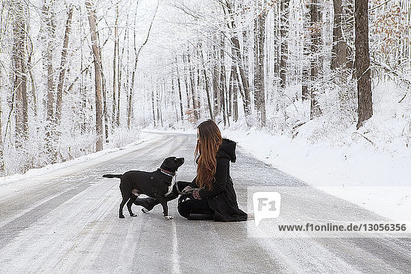 Side view of woman with dog on road during winter