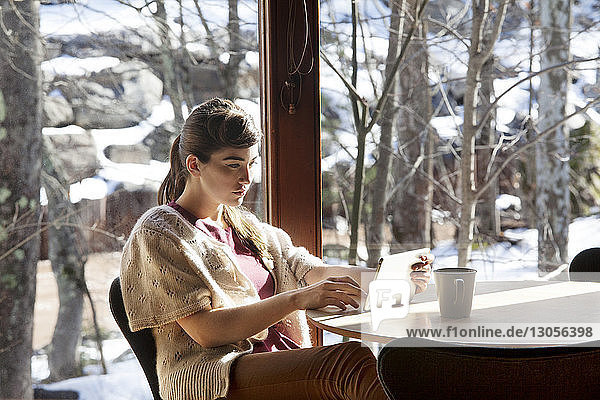 Frau benutzt Tablet-Computer  während sie auf einem Stuhl im Café sitzt