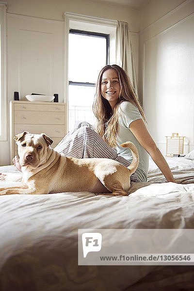 Porträt einer glücklichen Frau mit Hund auf dem Bett