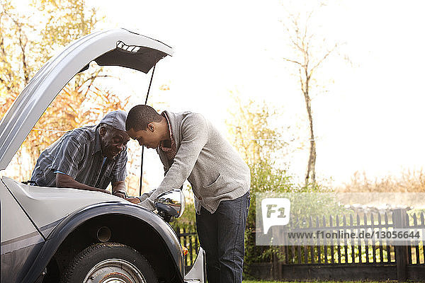 Vater und Sohn reparieren Auto gegen den Himmel