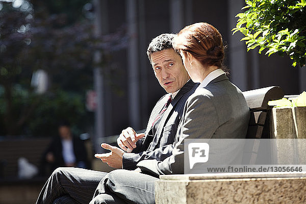 Geschäftsmann und Geschäftsfrau diskutieren auf der Bank sitzend