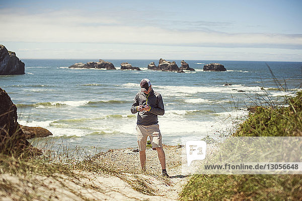 Man using smart phone while standing on shore