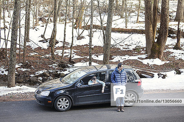 Woman sitting in car while man standing on road