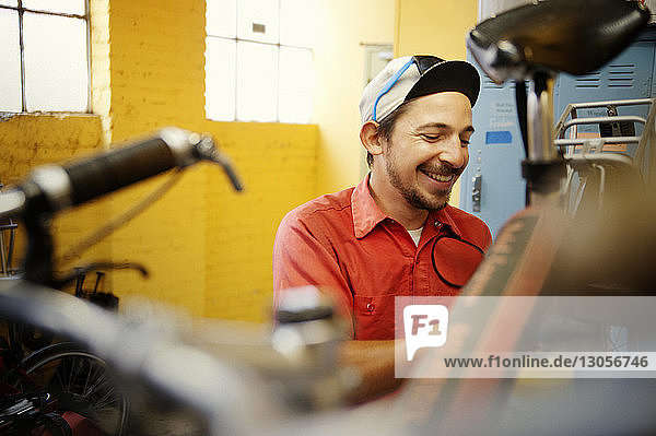 Glücklicher Mann repariert Fahrrad in Werkstatt