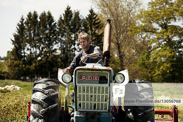 Landwirt zieht Egge mit Traktor auf dem Feld
