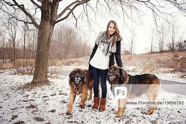 Porträt einer Frau  die mit Hunden auf einem schneebedeckten Feld steht