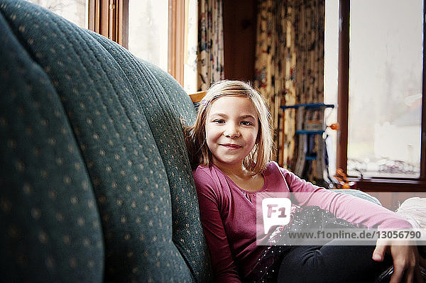 Porträt eines lächelnden Mädchens  das zu Hause auf dem Sofa sitzt