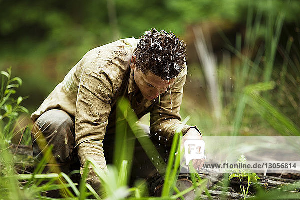 Landarbeiter wäscht sich das Gesicht  während er am Fluss im Wald sitzt