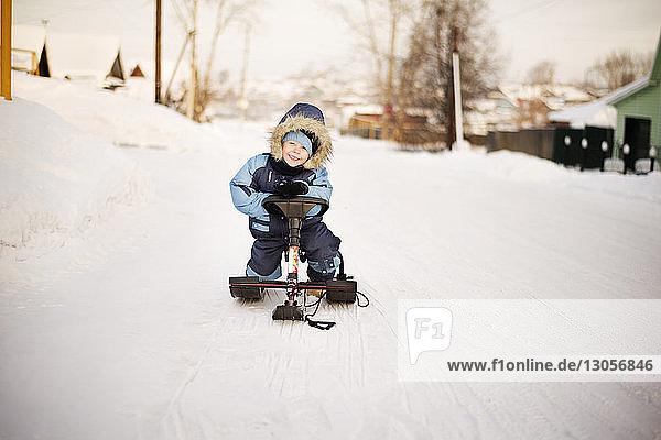 Portrait of happy boy sitting on sled during winter