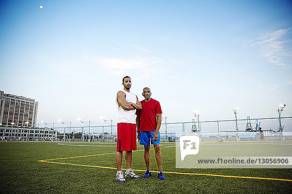 Porträt von Vater und Sohn auf einem Fußballfeld stehend gegen den Himmel