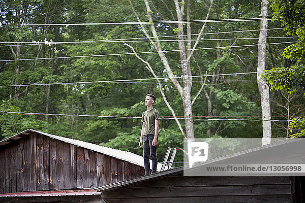 Teenager  der auf einem Dach gegen Bäume steht