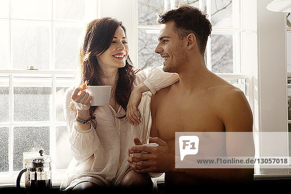 Glückliches Paar hält zu Hause Kaffeetassen in der Küche
