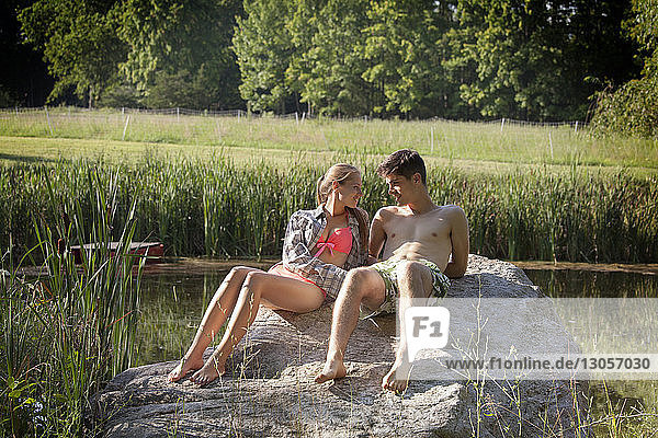 Young couple relaxing on rock at lakeshore