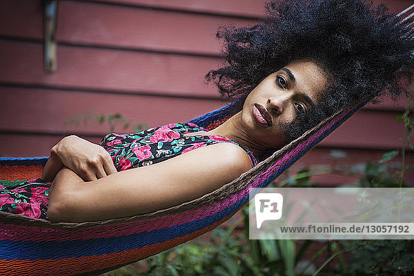 Woman with arms crossed relaxing on hammock in lawn