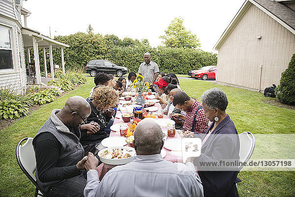 Family and friends eating food at picnic table