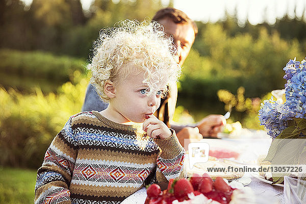 Boy eating food with grandfather on picnic table