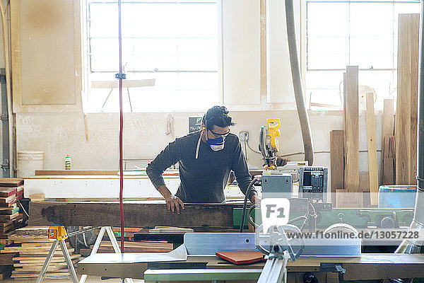 Male carpenter cutting wood in workshop
