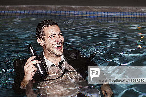 Glücklicher Mann mit Bärenflasche im Schwimmbad