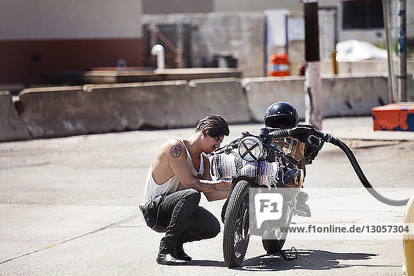 Seitenansicht eines Mannes beim Betanken eines Motorrads an der Kraftstoffpumpe