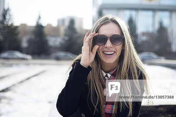 Portrait of happy woman holding sunglasses