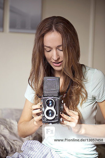 Close-up of woman using camera on bed