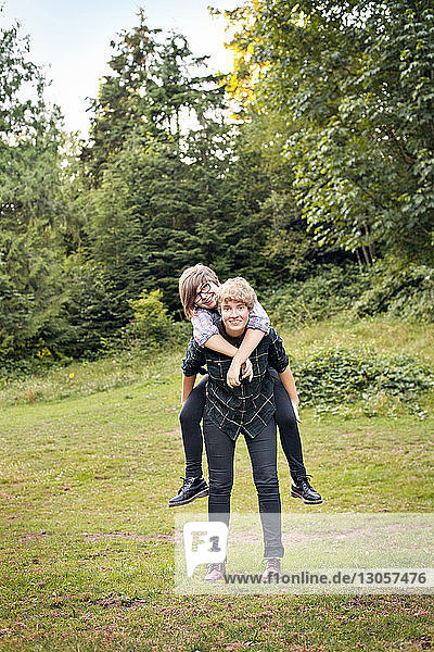 Portrait of couple piggybacking while standing on field