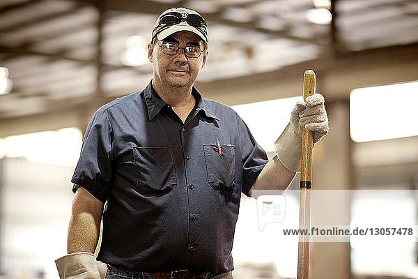 Porträt eines Mannes  der in der Metallindustrie stehend Ausrüstung hält