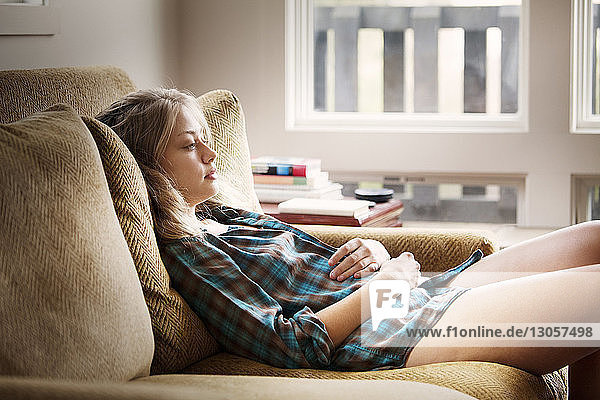 Woman looking away while relaxing on sofa at home