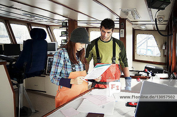 Mann und Frau überprüfen Dokumente im Fischerboot