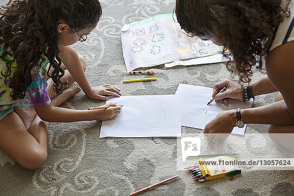 Hochwinkelansicht von Mutter und Tochter  die zu Hause auf Papier zeichnen