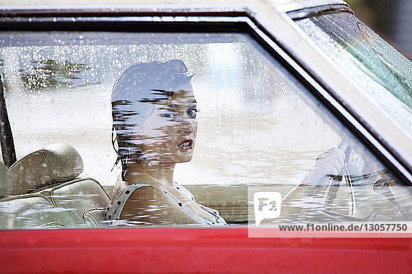 Porträt einer Frau  die das Lenkrad hält  während sie im Auto sitzt