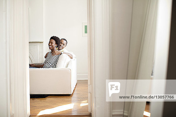 Happy couple sitting on sofa at home