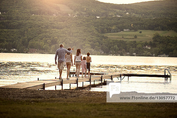 Rückansicht einer Familie  die auf einem Steg über den See geht