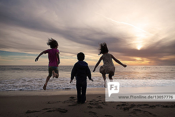 Kinder genießen am Ufer während des Sonnenuntergangs