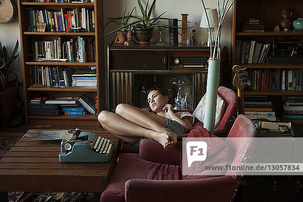 Nachdenkliche Frau entspannt sich zu Hause auf Sesseln