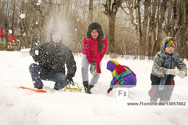 Cheerful family playing with snow on field