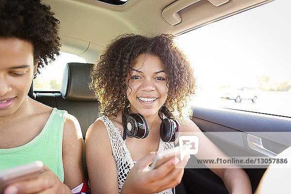 Porträt einer Frau  die telefoniert  während sie im Auto neben einem Freund sitzt