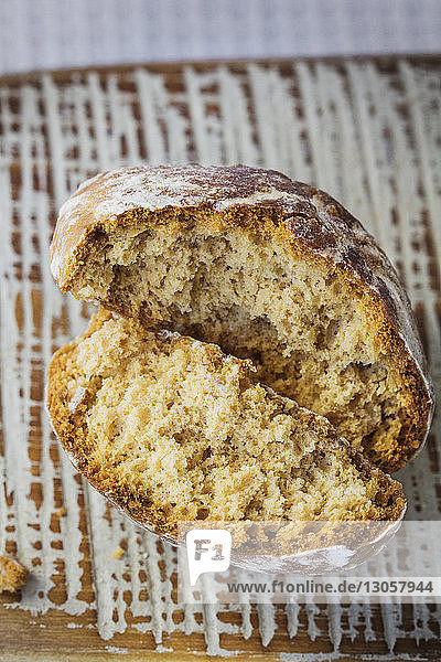 Nahaufnahme von gebrochenem Brot auf Schneidebrett bei Tisch