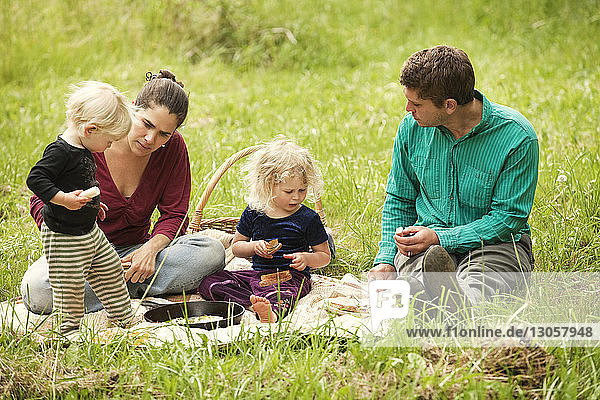 Family having food while sitting on grassy field