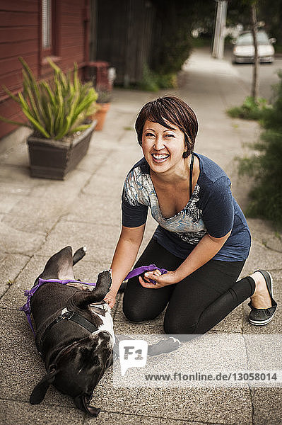 Porträt einer Frau  die mit einem Hund auf einem Fußweg spielt