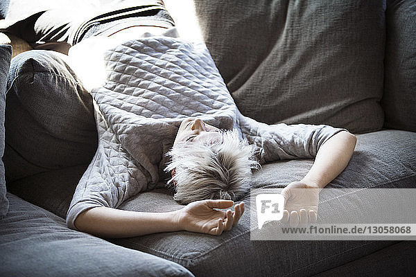 Junge Frau liegt kopfüber auf dem Sofa zu Hause