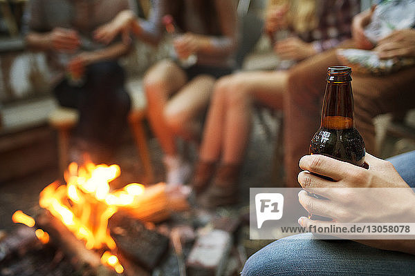 Ausgeschnittenes Bild eines Mannes  der beim Zelten mit Freunden eine Bierflasche hält