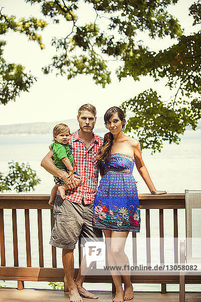Portrait of family standing by railing against lake