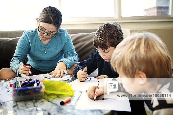 Kinder  die zu Hause sitzen und auf Papier zeichnen