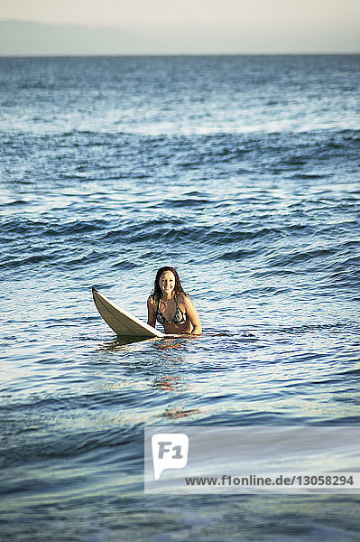 Lächelnde Frau beim Surfen im Meer