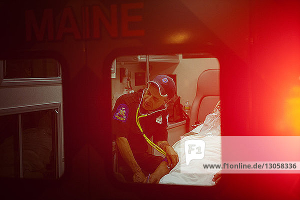 Sanitäter untersucht Patient mit Stethoskop im Krankenwagen