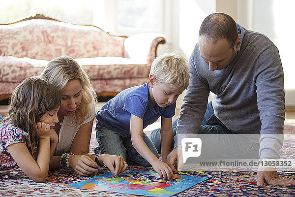 Familie spielt zu Hause Puzzle auf dem Boden