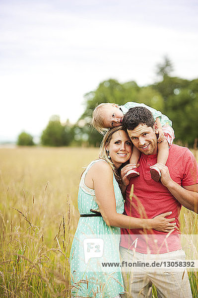 Happy family enjoying on grassy field against sky
