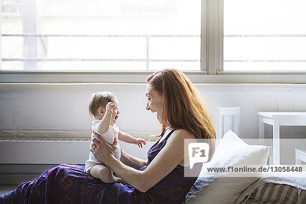 Seitenansicht einer Frau  die mit ihrer Tochter spielt  während sie zu Hause sitzt